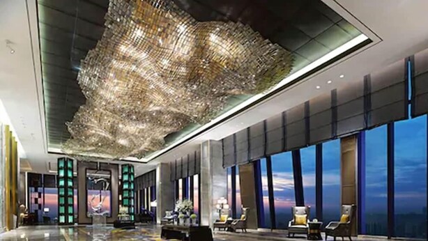 A spacious lobby with a large chandelier, seating area, and large windows offering a view of the cityscape. - Wanda Vista Zhengzhou (Zhengzhou)