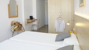 A bedroom with a bed, a desk with a laptop, a chair, a wardrobe, and a hanging garment. - Bell Repos (Castell-Platja d'Aro)