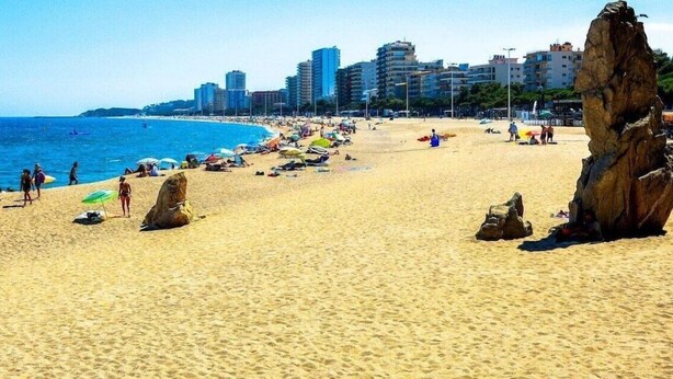 A beach with clear blue water, sandy shore, and rocky formations. - Bell Repos (Castell-Platja d'Aro)
