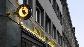 Un edificio con un cartel que dice "HOTEL CITY ZURICH" y un emblema circular con un ave.