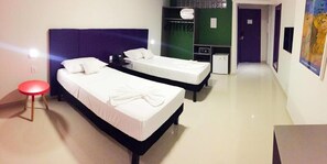 A hotel room with two single beds, a red stool, a wardrobe, and a bathroom visible through an open door. - Rede Andrade Docas (Belém)