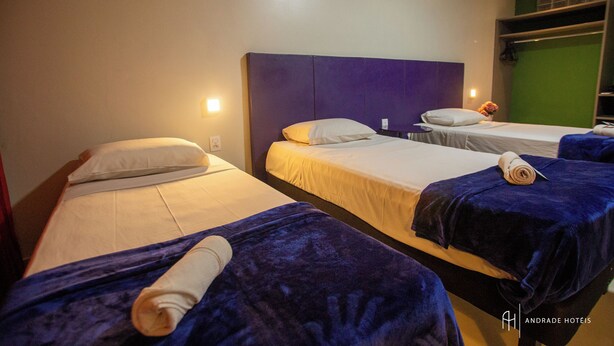 A hotel room with three beds, each with a different headboard color. - Rede Andrade Docas (Belém)