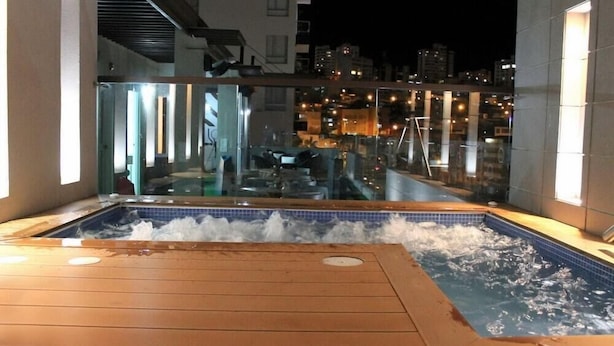 Un jacuzzi en un balcón con vista a la ciudad por la noche.