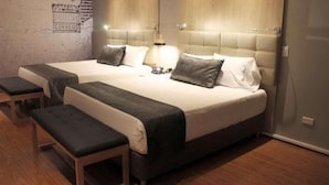 Habitación de hotel con dos camas, un banco y un cartel en la pared.