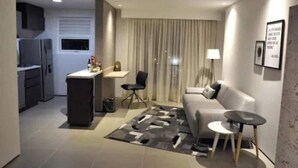 Una sala de estar moderna con un sofá, una mesa de centro y una zona de comedor con una pequeña mesa y sillas.