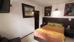 Quarto com cama, mesa de cabeceira, cadeira e porta.