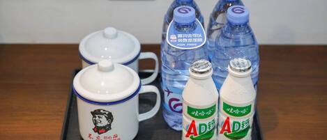 Un plateau avec une théière, deux bouteilles d’eau et deux bouteilles d’une boisson dont l’étiquette indique « AD ».