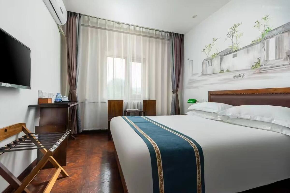 Habitación de hotel con una cama grande, televisión de pantalla plana, escritorio con silla y un cuadro en la pared.