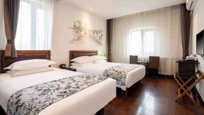 Una habitación de hotel con dos camas, un escritorio, una silla, un televisor y un cuadro en la pared.