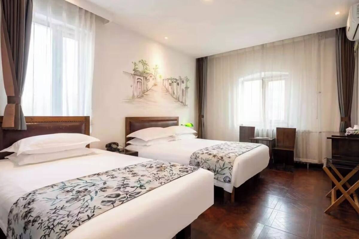 Una habitación de hotel con dos camas, un escritorio, una silla, un televisor y un cuadro en la pared.