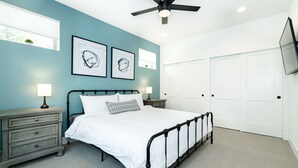 A bedroom with a bed, bedside tables, a ceiling fan, and a wardrobe.