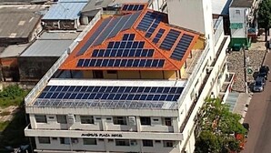 Un hotel con techo plano cubierto de paneles solares, una tienda en la planta baja y un estacionamiento.