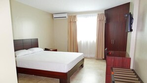 Una habitación de hotel con cama, escritorio, armario y televisión.