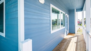 Ein blaues Haus mit einer Holzveranda, weißem Zierrat und einem kleinen weißen Zaun.