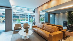 A modern interior with a leather sofa, a round coffee table, and a view of the outside through large windows. - Victory Suites (Juiz de Fora)