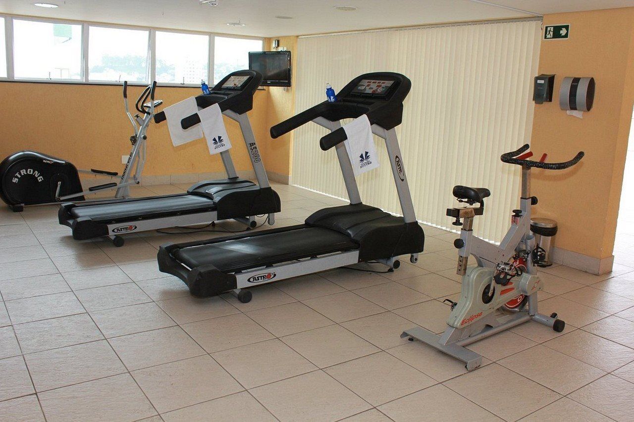 Un gimnasio con cintas de correr, elíptica y bicicleta estática.