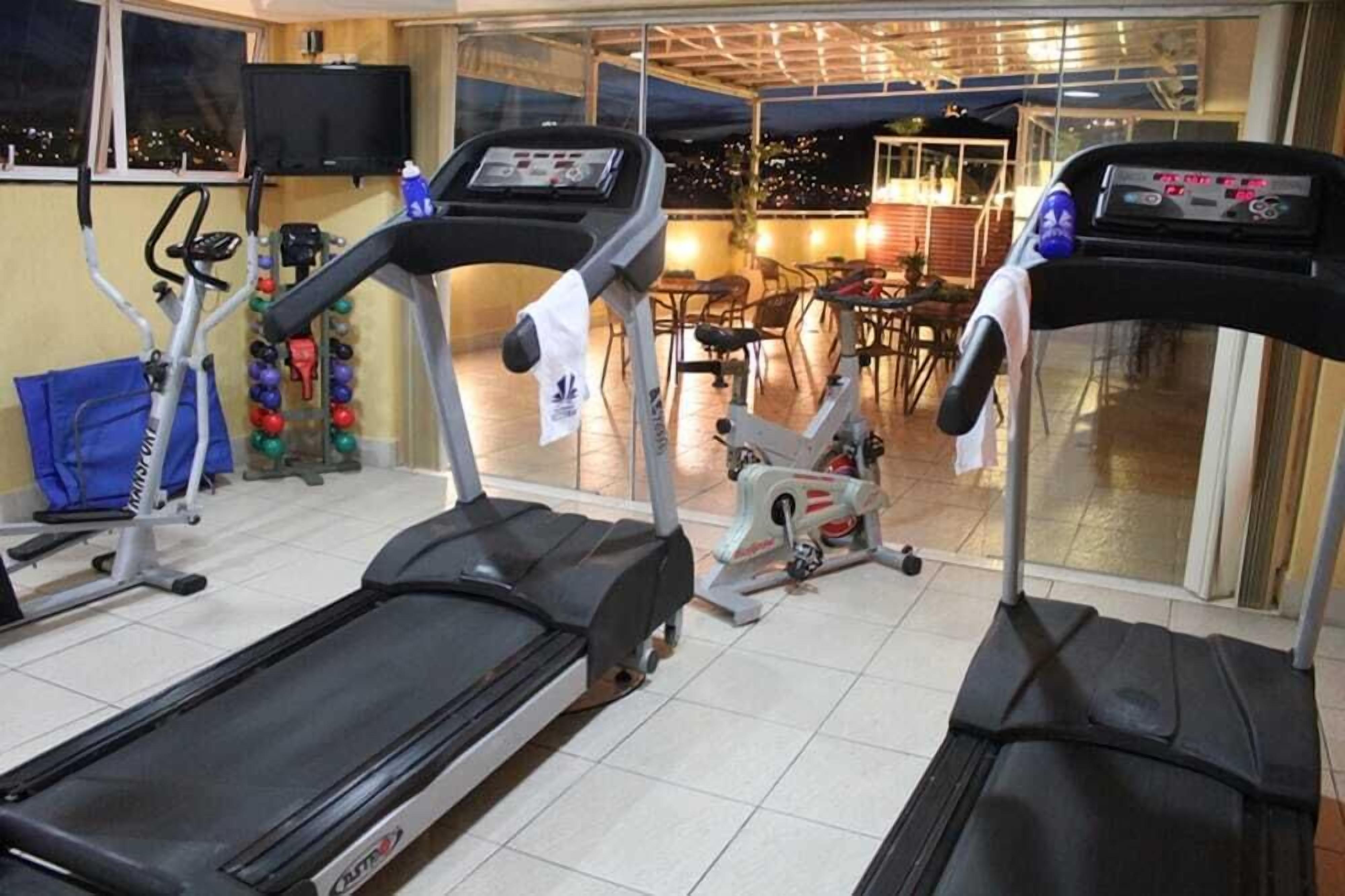 A gym with treadmills, exercise balls, and a TV.