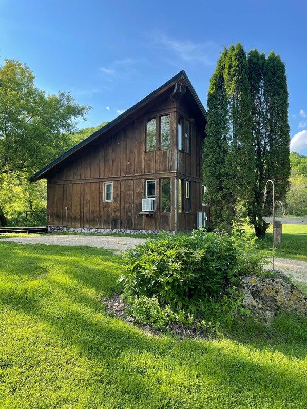 A rustic wooden building with a sloped roof, large windows, and a stone foundation.