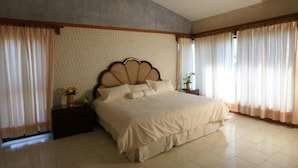 Un dormitorio con una cama grande, una mesita de noche y una ventana con cortinas.