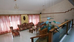 Amplia sala de estar con un conjunto de sofá de madera, una mesa de centro y una barandilla de cristal que da a una escalera.