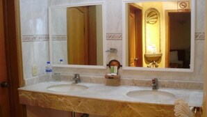 Un baño con dos lavamanos, un espejo grande y un perchero para toallas.
