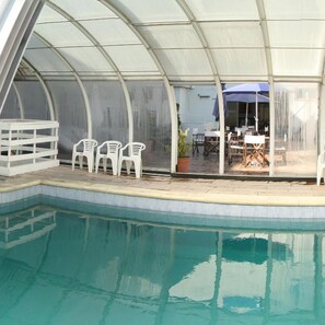 A pool area with a covered seating area, chairs, and a table. - Hotel Libertador Pinamar (Pinamar)