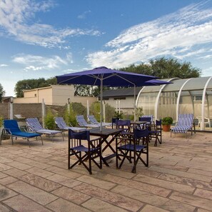 An outdoor patio with a table and chairs, a covered seating area, and a greenhouse structure. - Hotel Libertador Pinamar (Pinamar)