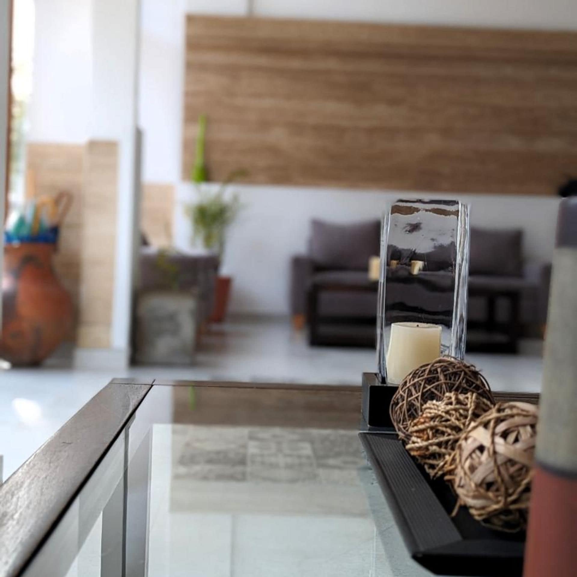 A modern living room with a glass coffee table, a candle, and decorative items.