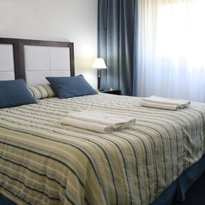 A hotel room with a bed, pillows, a lamp, and a window with curtains. - Hotel Libertador Pinamar (Pinamar)