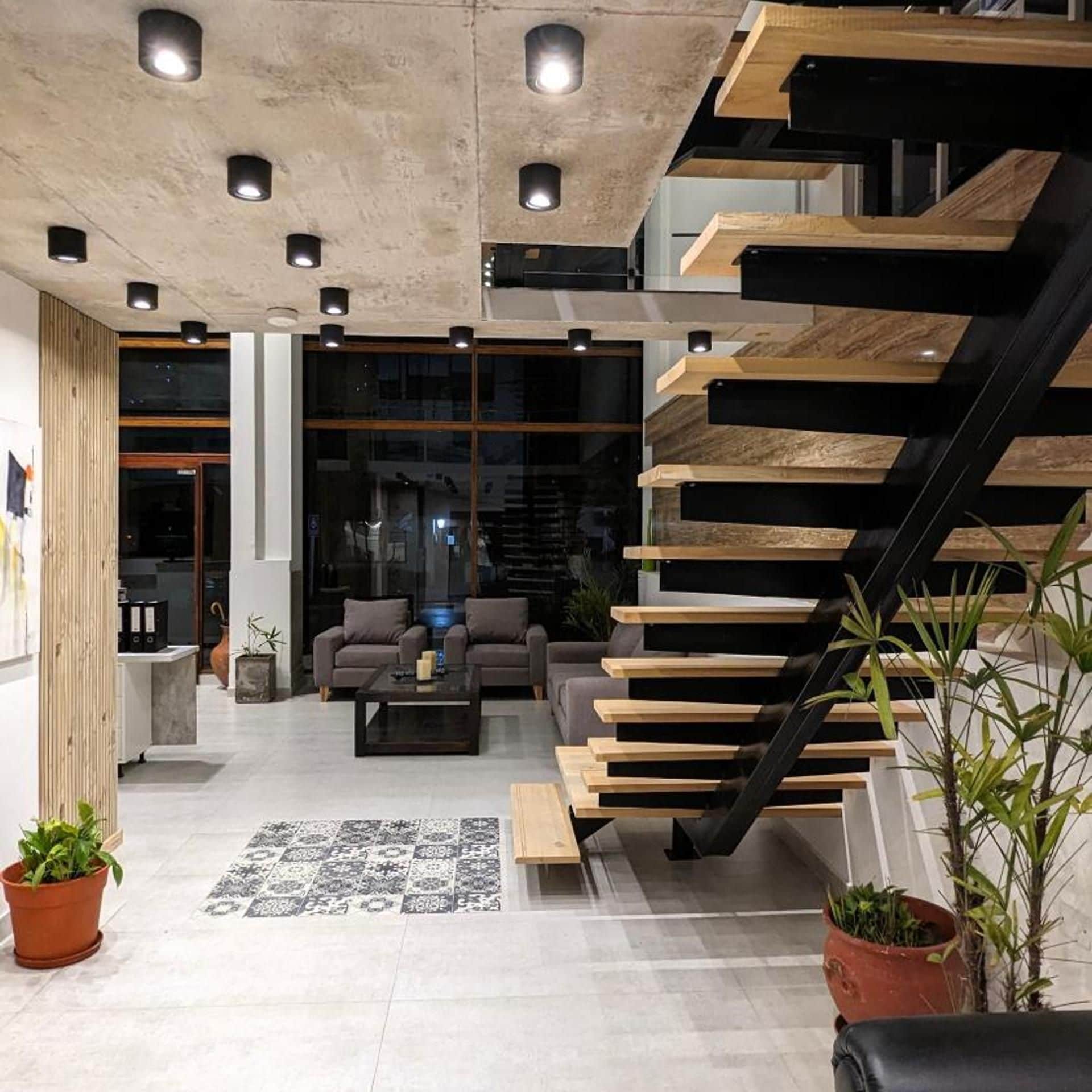 A modern interior with a staircase, seating area, and a large window.