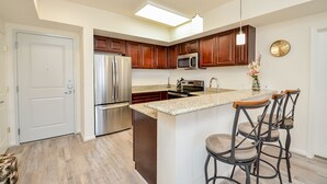 A modern kitchen with a central island, stainless steel appliances, and dark wooden cabinets. - Spacious Cozy Home in Lifestyle Center| Gated Condo |3B (Katy)