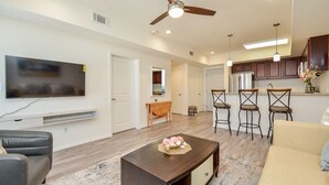 A modern living room with a flat-screen TV, a dark wooden coffee table, and a beige sofa. - Spacious Cozy Home in Lifestyle Center| Gated Condo |3B (Katy)