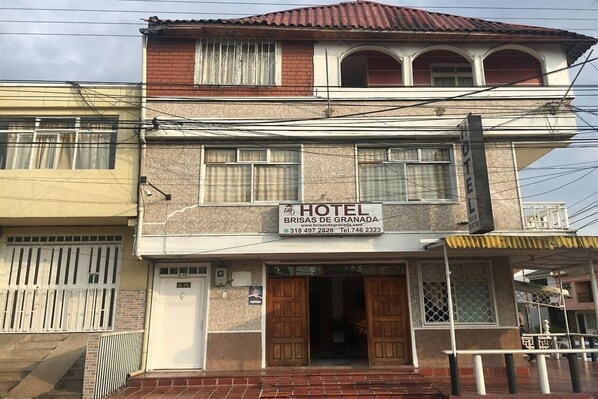 A two-story building with a sign indicating it is a hotel named "Brisas de Granada."