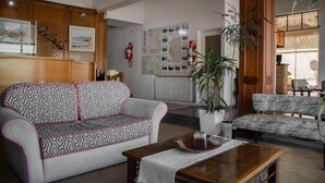 Un hall con un sofá estampado, una mesa de centro de madera y una planta en maceta.