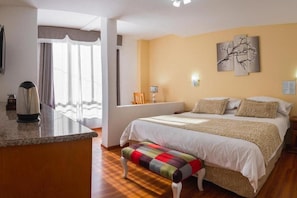 Une chambre à coucher avec un lit, un banc et une vue sur l’extérieur.