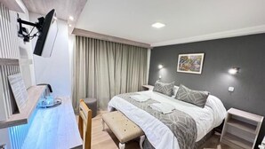 Un dormitorio moderno con cama, mesitas de noche, escritorio y silla.