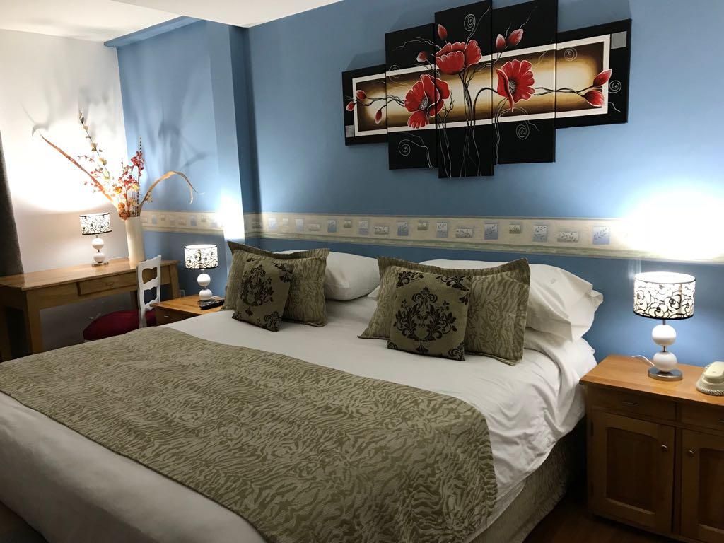 A bedroom with a bed, nightstands, a wall-mounted artwork, and a decorative vase.
