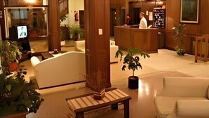 Un hall de hotel con mostrador de recepción, zona de estar y televisor.
