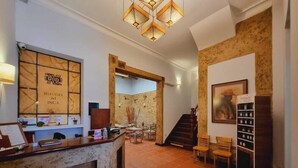A reception area with a wooden reception desk, a wall-mounted sign reading "Refugio del Inca", and a staircase leading to another level.