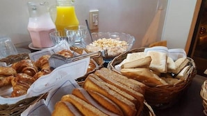 A breakfast buffet with bread, pastries, and juice.
