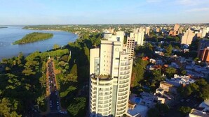 A high-rise hotel with a view of a river and surrounding greenery. - Maran Suites And Towers (Parana)