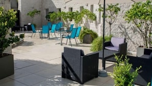 An outdoor patio area with a table and chairs, a large umbrella, and potted plants. - Maran Suites And Towers (Parana)