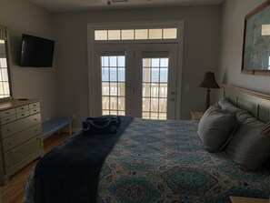 Ein Schlafzimmer mit Bett, Schminktisch, Fernseher und Balkontür.