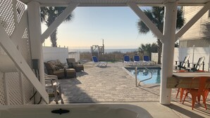 Ein Poolbereich mit Liegestühlen, einem Whirlpool und Blick aufs Meer.
