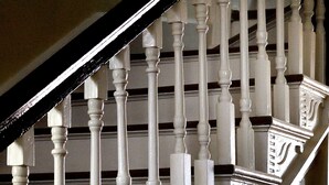 Escada com balaústres brancos e corrimão escuro.