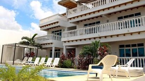 A multi-story hotel with balconies, a swimming pool, and lounge chairs. - Aria Hotel Spa (Cartagena)