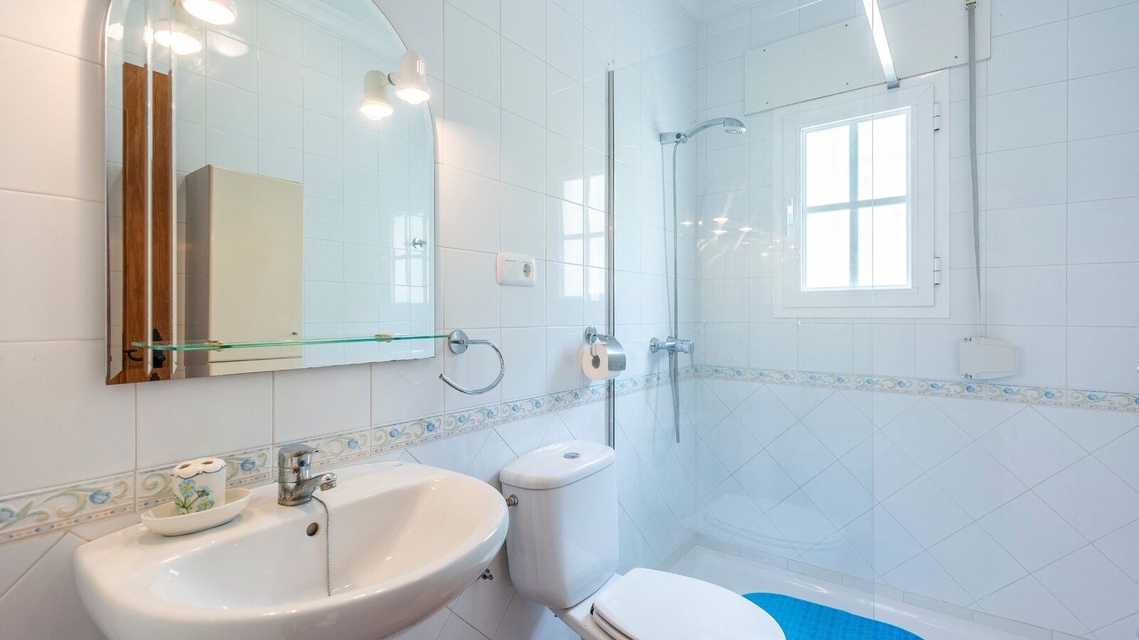 Ein modernes Badezimmer mit Duschkabine aus Glas, einem weißen Waschbecken und einer Toilette.