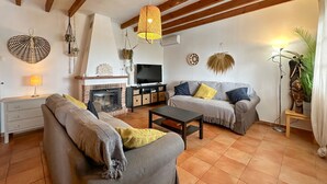 A cozy living room with a fireplace, two sofas, a coffee table, and various decorative items. - Villa Hugo Cómpeta by Ruralidays (Málaga)