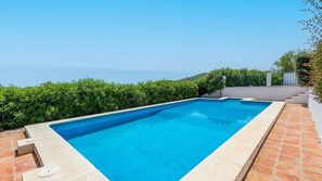 Relax by the serene pool surrounded by lush greenery and a white fence.