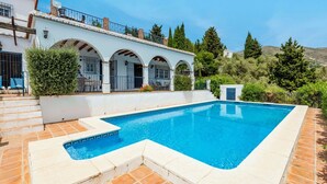 A rectangular swimming pool with a tiled edge, surrounded by a white building with arched windows and a tiled roof. - Villa Hugo Cómpeta by Ruralidays (Málaga)